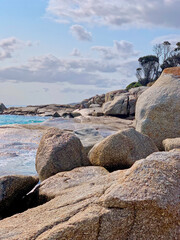 Fototapeta na wymiar Ocean inlet at Bay of Fires. Boulders covered in orange lichen, turquoise water, cloudy sky. No people, space for copy