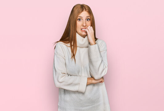 Young irish woman wearing casual winter sweater looking stressed and nervous with hands on mouth biting nails. anxiety problem.