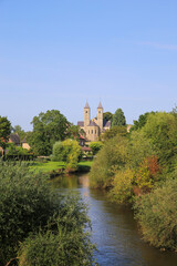 View over small river Roer with green trees on roman catholic basilica with monastery  from 11th century against blue summer sky - Sint Odilienberg (near Roermond) - Netherlands