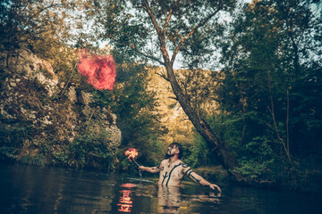 Man in a river blowing fire