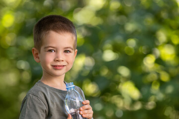 little boy with plastic bottle of water outdoors