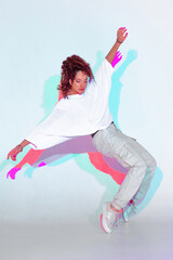 Dancing mixed race young girl in colourful light. Female dancer showing contemporary hip hop dance...