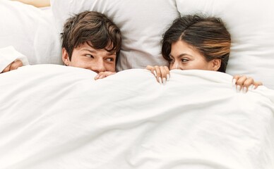 Young caucasian couple smiling happy lying on the bed at home.