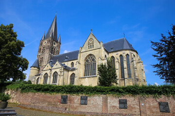 Fototapeta na wymiar Thorn (Limburg), Netherlands - July 9. 2021: View on roman abbey church with trees against blus summer sky