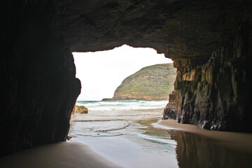 View out of the Remarkable cave to the sea. Waves washing over the sandy floor. No people.
