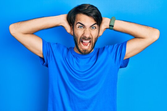 Young hispanic man wearing casual clothes crazy and scared with hands on head, afraid and surprised of shock with open mouth