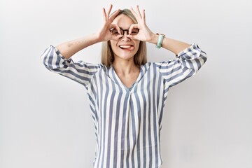 Asian young woman wearing casual clothes and glasses doing ok gesture like binoculars sticking tongue out, eyes looking through fingers. crazy expression.