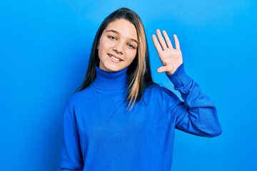 Young brunette girl wearing turtleneck sweater waiving saying hello happy and smiling, friendly welcome gesture