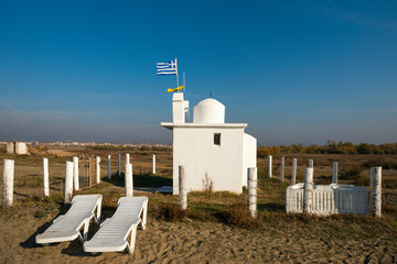 Whitewashed Greek Orthodox hermitage with a flag blowing in the wind on a nearby Alexandroupolis beach