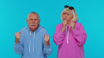 Upset frustrated annoyed senior stylish grandparents pensioners raising hands in indignant...