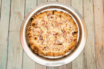 Pizza a la carbonara cooked in a stone oven with well-cooked edges, with guanciale, mushrooms and red onion on a metal tray