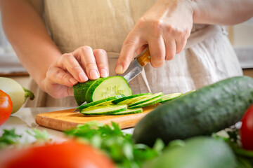 Chef slicing cucumber on the table in restaurant. Process of cutting vegetables in kitchen.