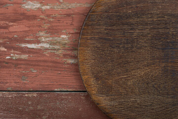 Circle cutting board on a red wooden table. Food preparation tool and kitchen utensils.
