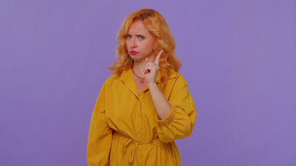 I am warning you. Lovely girl shakes finger and saying no, be careful, scolding and giving advice to avoid danger mistake, disapproval sign. Young woman studio shot isolated on purple wall background