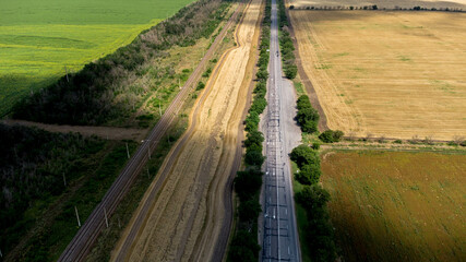 Track and railway running through wheat fields and sunflower fields aerial photography