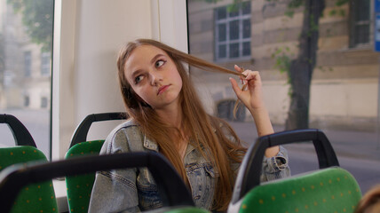 Tired and depressed young woman sitting alone near the public bus transport window after hard work...