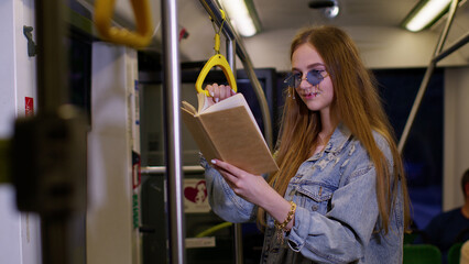 Portrait of attractive young adult woman stay at empty subway train and reading interesting book....