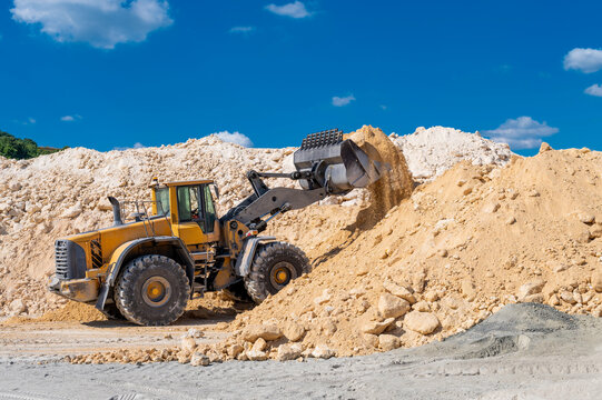 Front end loader in operation, dumping limestone 