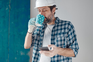 Construction engineer on a morning coffee break using mobile phone