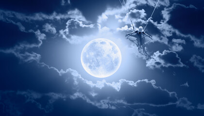 Naklejka na ściany i meble Beautiful girl riding a swing on the space on a full moon at night 