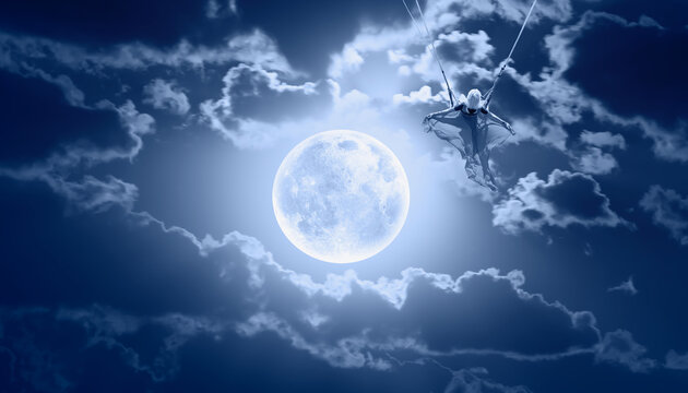 Beautiful girl riding a swing on the space on a full moon at night "Elements of this image furnished by NASA"