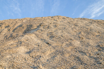 Mountain of sandy gravel mixture on the background of the sky.