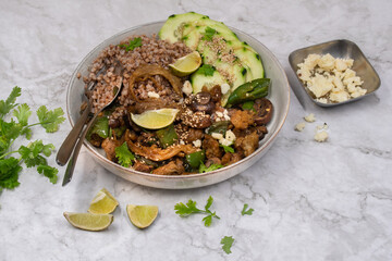Vegan seitan stir fry bowl with buckwheat, mushroom, pepper and cucumbers