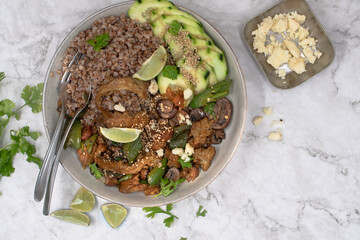Vegan seitan stir fry bowl with buckwheat, mushroom, pepper and cucumbers