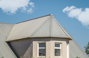 The roof of the house from a galvanized metal profile against the sky.