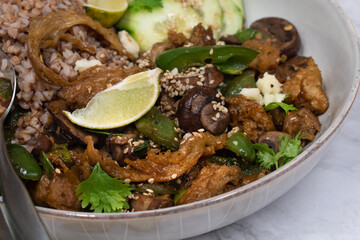 Vegan seitan stir fry bowl with buckwheat, mushroom, pepper and cucumbers