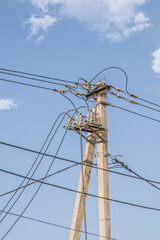 Electrical insulators on a concrete pole on the street against the background of the sky. Aerial electrical engineering structures.