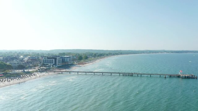 Aerial drone view flying above Baltic sea pier beach in Scharbeutz, Germany, summer sunny day, circle pan