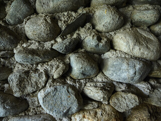 Detail of an old stone wall. The stones are fixed with cement. 