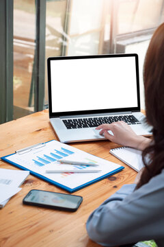 Vertical view image of woman hand using laptop computer with blank white screen while sitting at the table.