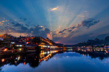 Naklejka na ściany i meble beautiful sunsets view of Ban rak thai, Mae Hong Son, Thailand. The dusk scene after sunset with the reflection of the buildings and night market on the pond.