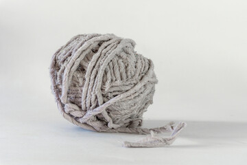 Side view of a grey thread ball from recycled textiles on white background