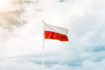 Beautiful Polish flag with cloudy sky on background