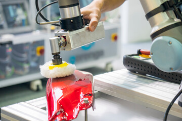 The engineer checking robotic arm polishing the automotive painting parts.