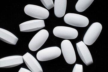 Several vitamin tablets on a black ceramic dish, close-up, top view.