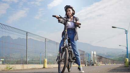 Fototapeta na wymiar Young Asian woman break ride bicycle before go to work