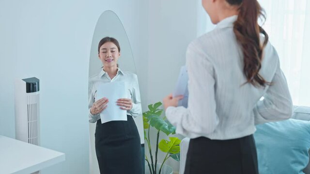 Asian applicant prepare for job interview in front of mirror at home.