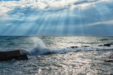 Calm seascape with stormy sky where sun-rays get through the clouds.