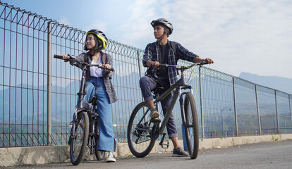 Fototapeta na wymiar young asian couple having rest after ride bicycle go to work
