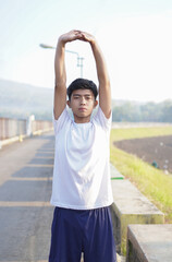 young asian man having streaching before jogging in the morning