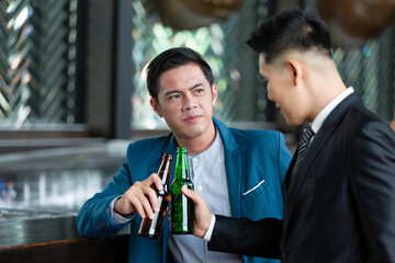 Group of Asian businesspeople talking and drinking beer in conference room. They are all standing, wearing suits and happy smiling. business, people concept