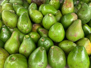A background with a bunch of green avocados on display in the market.