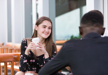Young attractive female sitting with colleagues during take a break. Woman sitting and using digital tablet at the creative office or coffee shop.