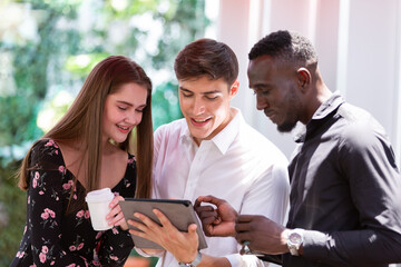 Group of young business people and creative. They are standing, smiling and using digital tablet together at the creative office or coffee shop. business, people, office concept