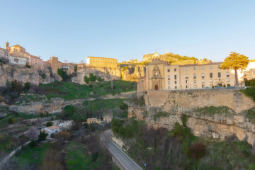 Fototapeta na wymiar Cityscape in old city changing light at sunset; Parador nacional , former Convent of San Pablo with old town hanging over mountain in Cuenca, World Heritage Site, Spain. Horizontal view