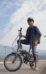 asian young man with backpack having rest after ride bicycle